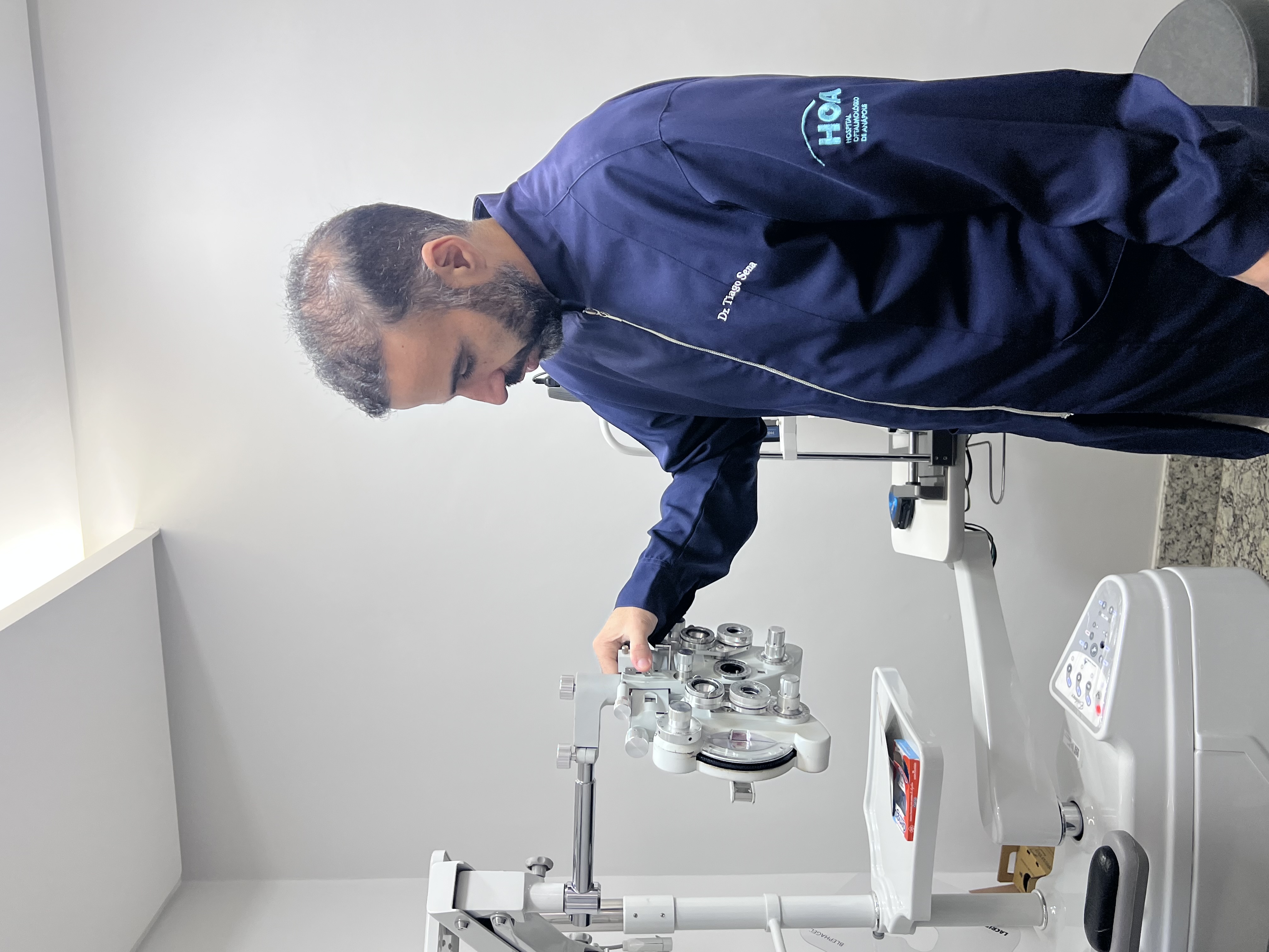 Dr. Tiago Sena no consultório com equipamento oftalmológico